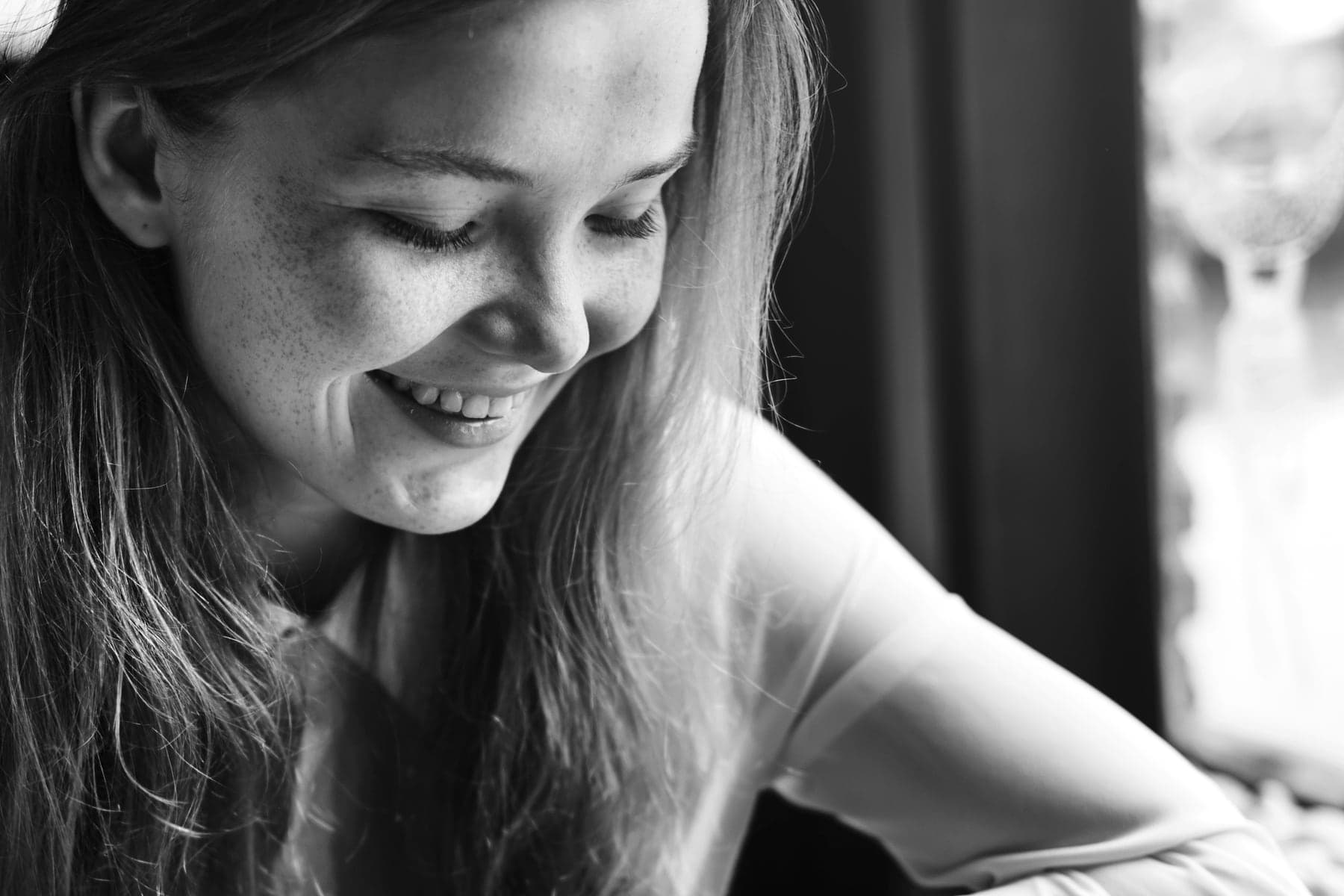 A woman smiling as she looks down at the table in front of her