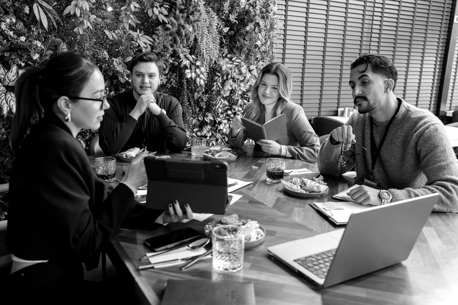 Four colleagues around a table as one of them talks the others through something on a tablet